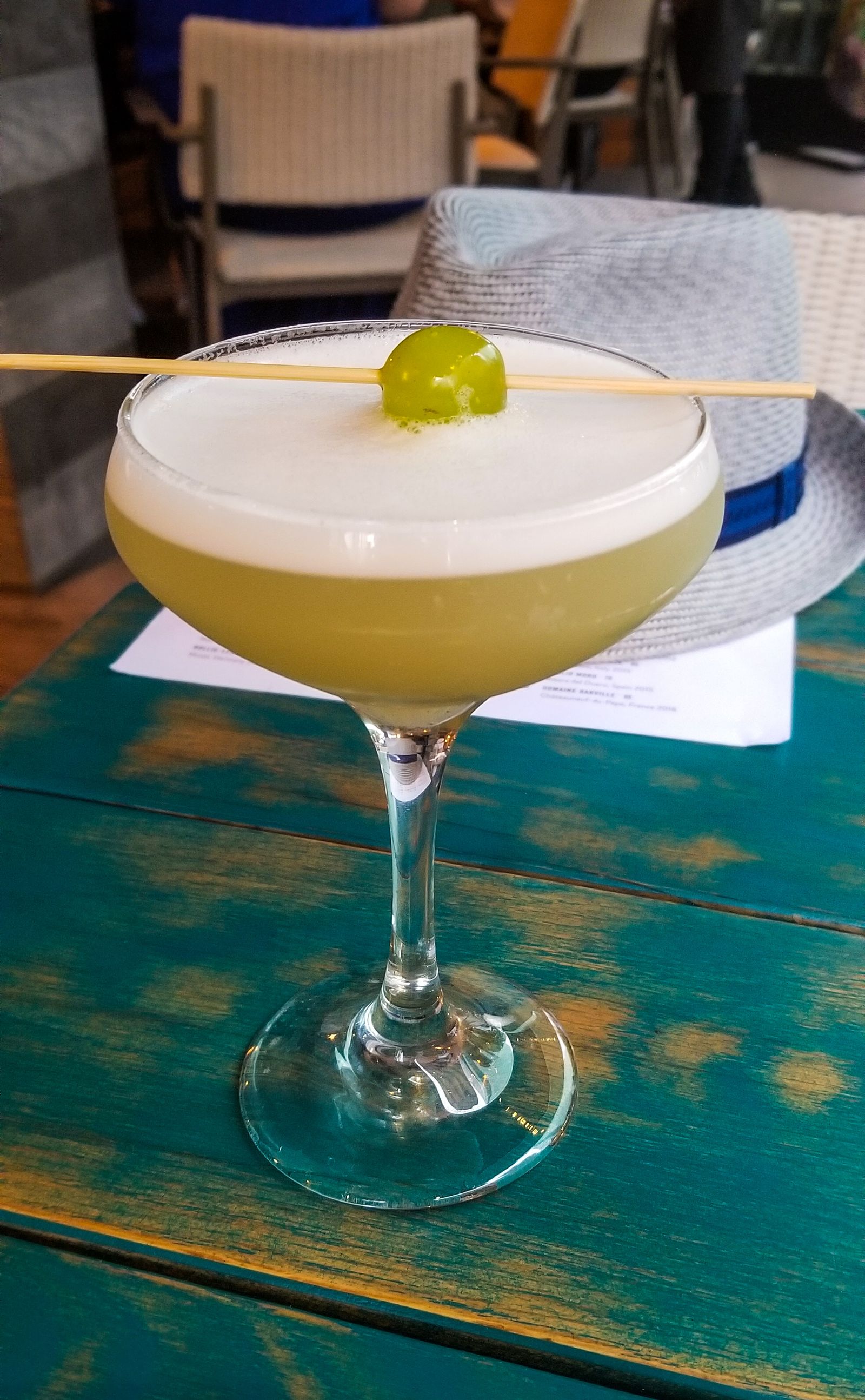 A pisco sour with a lime wheel on a bar table