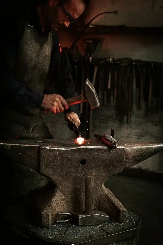 An artisan working metal on an anvil