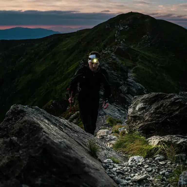 A hiker with a headlamp on the ridge of Cerro Manquehuito at dawn