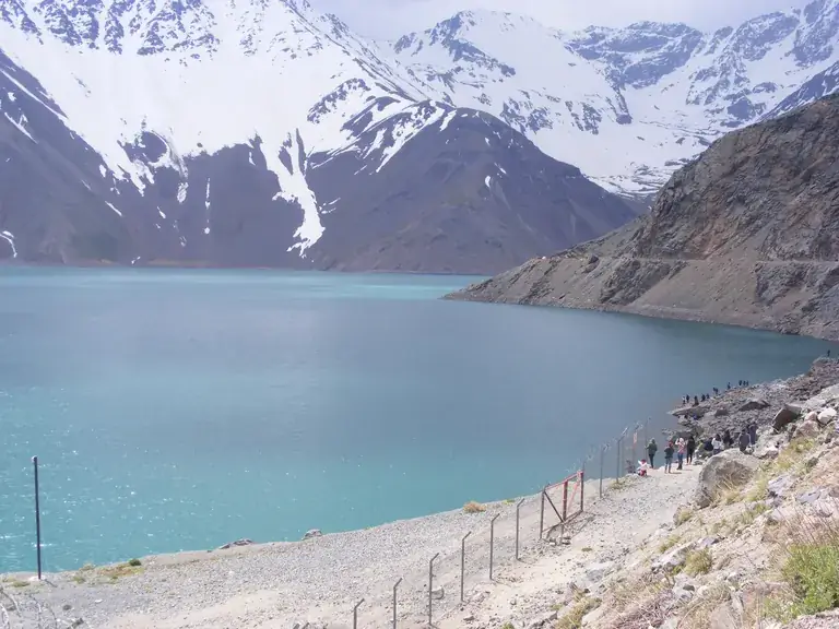 Travellers looking over the turquoise El Yeso reservoir in the Andes, Cajón del Maipo