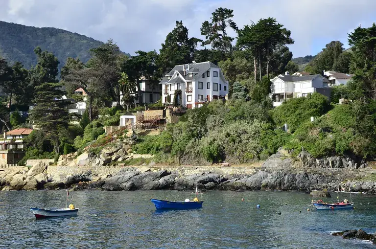 Fishing boats in the cove of Zapallar, with houses among the trees